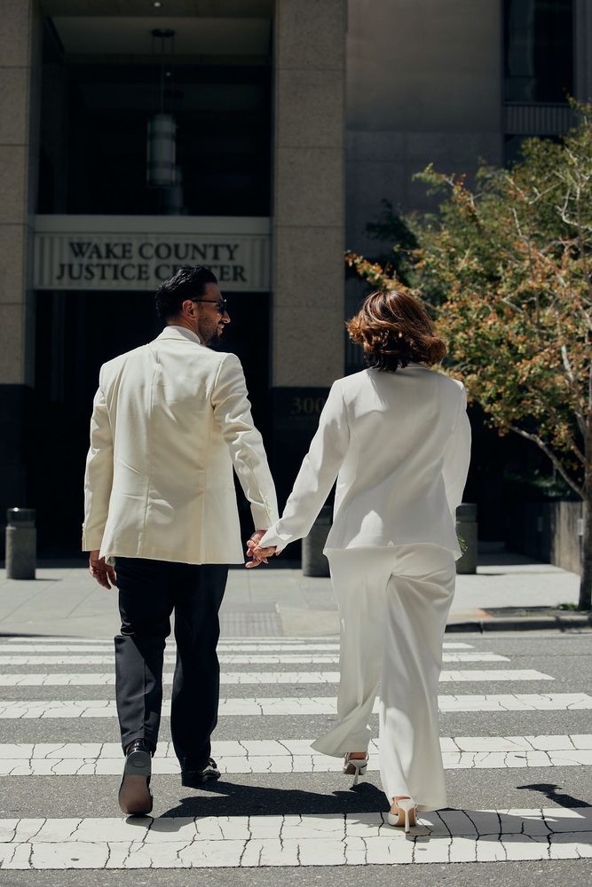 Couple seen from behind crossing toward the Wake County Justice Center entrance, holding hands