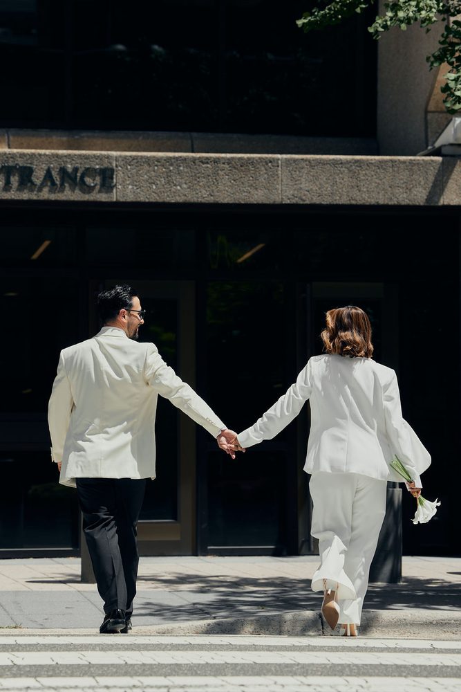 Newlyweds stepping up to the courthouse entrance hand in hand, calla lilies trailing from the bride's hand