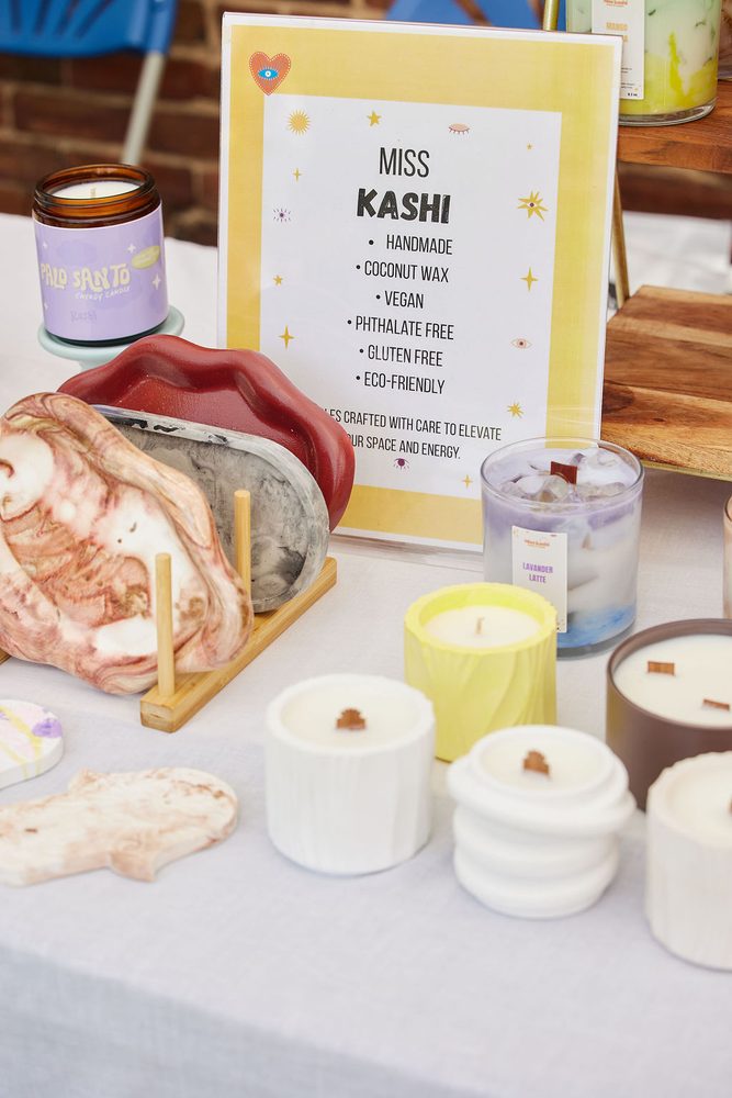 Handmade candles and marbled trays on a vendor table with a framed sign listing coconut wax and eco-friendly features