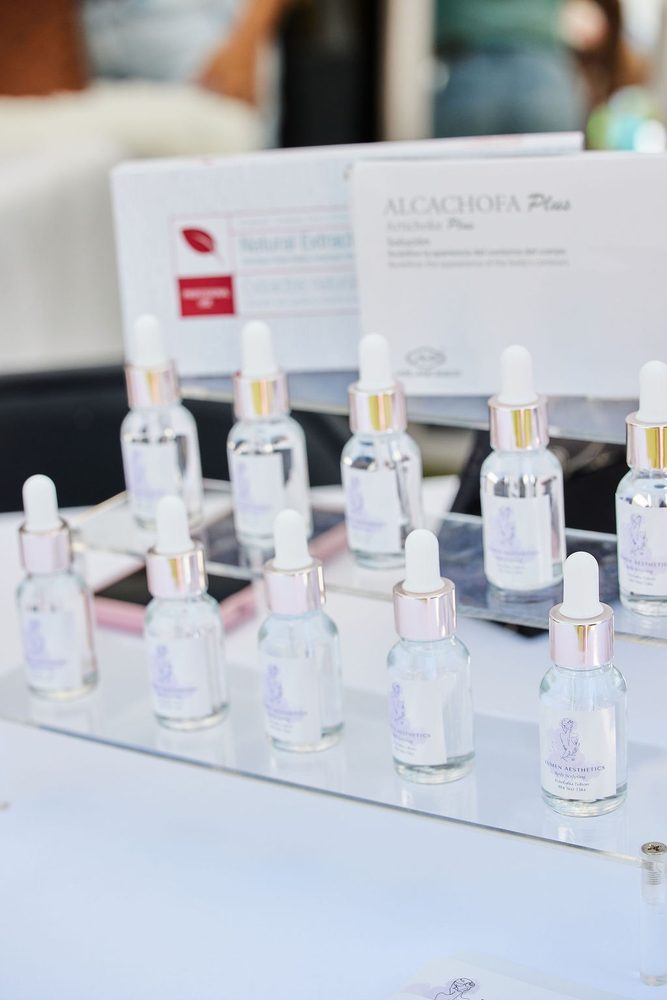 Rows of glass dropper serum bottles with rose-gold caps on clear acrylic risers at a skincare booth