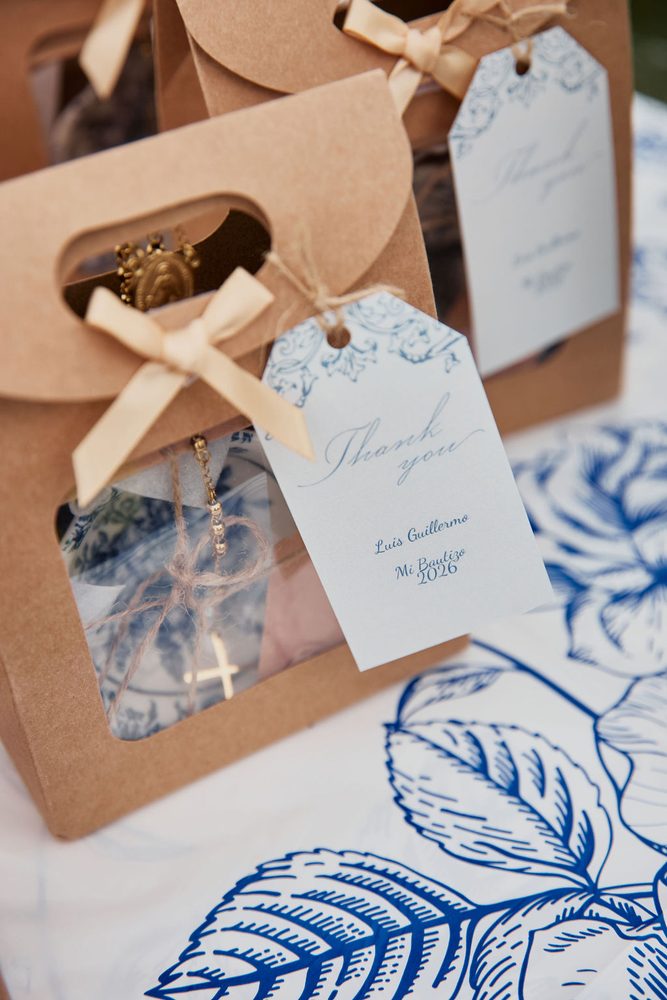 Close-up of a kraft favor bag with a cream bow, a small gold medal and a printed thank-you tag