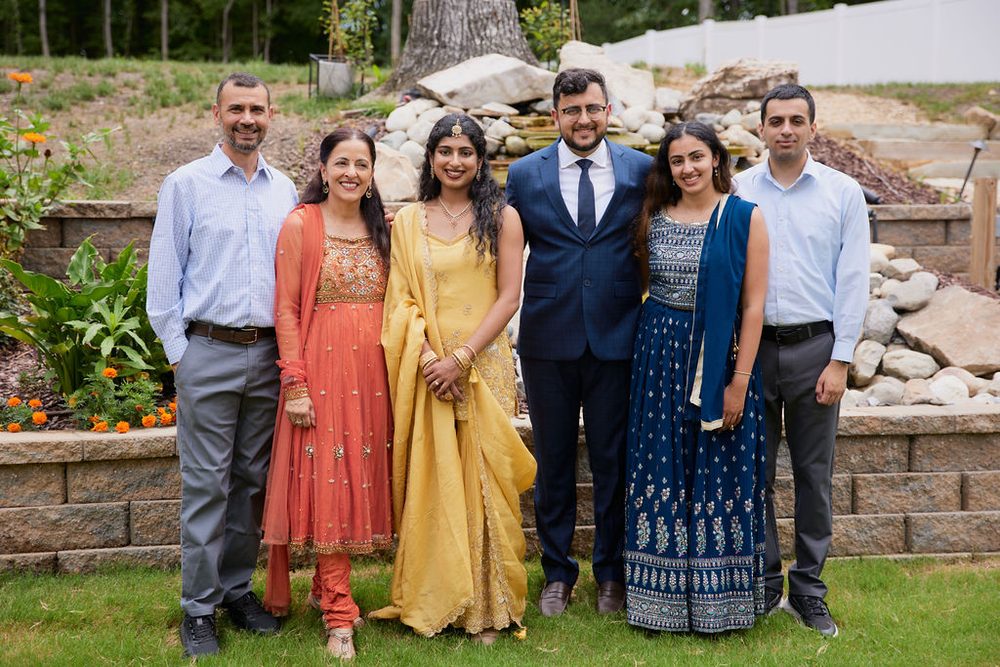 Couple posing with family in colorful embroidered outfits and dress shirts in a landscaped garden
