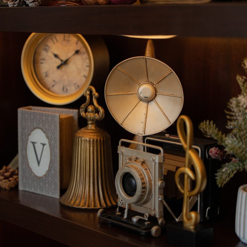 Repisa con reloj antiguo, camara vintage y clave de sol dorada